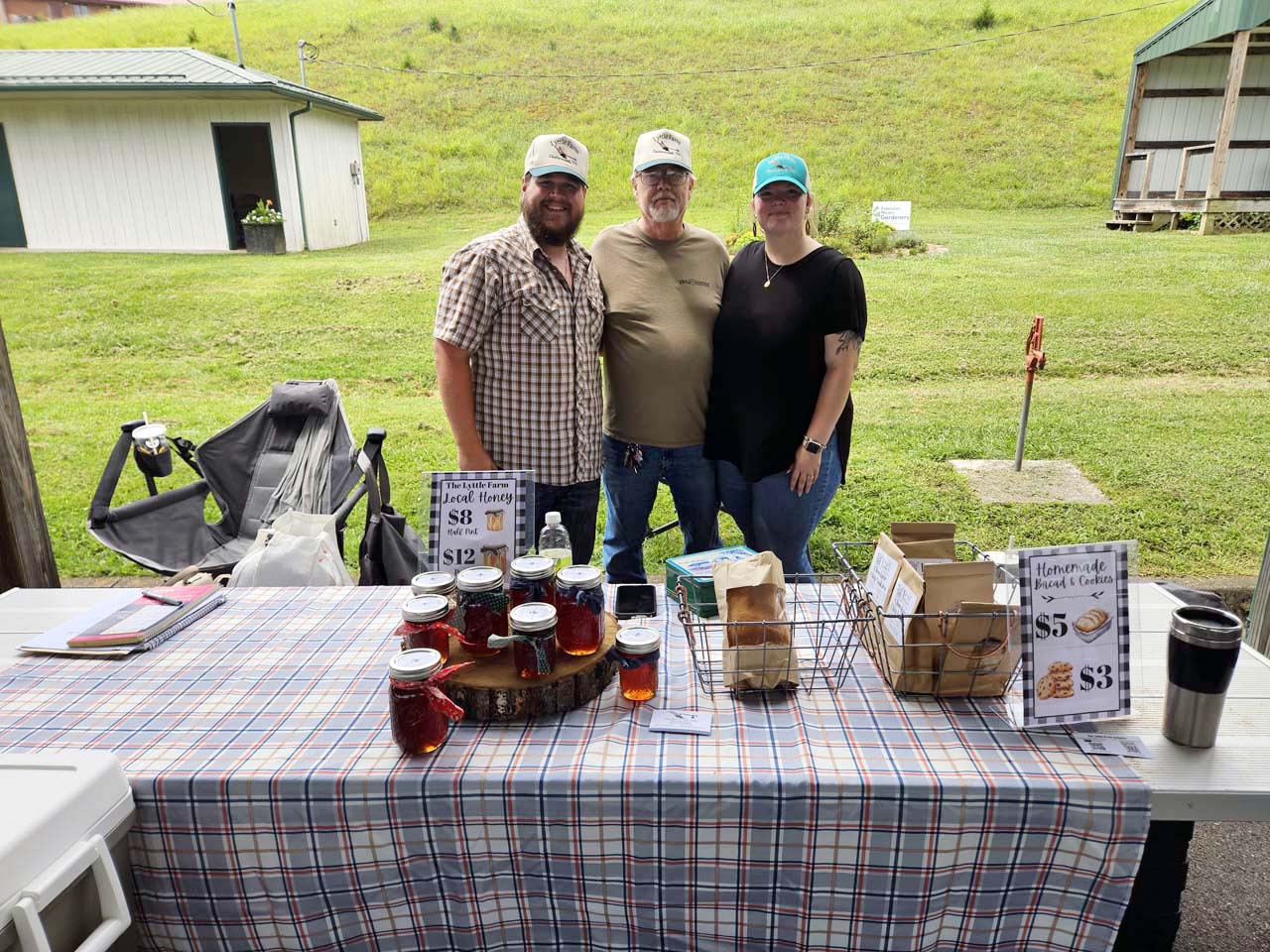 Travis Brooks, Jim Lyttle, and Shiloh Brooks pose in front of the Lyttle Farm Booth at the Lebanon Farmers Market.