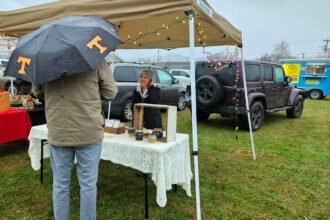 Man with Tennessee Vols umbrella stands at a vendor booth