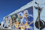 Colorful brick mural showing people playing guitars and singing, with 'Birthplace/Country Music' text along the top edge.