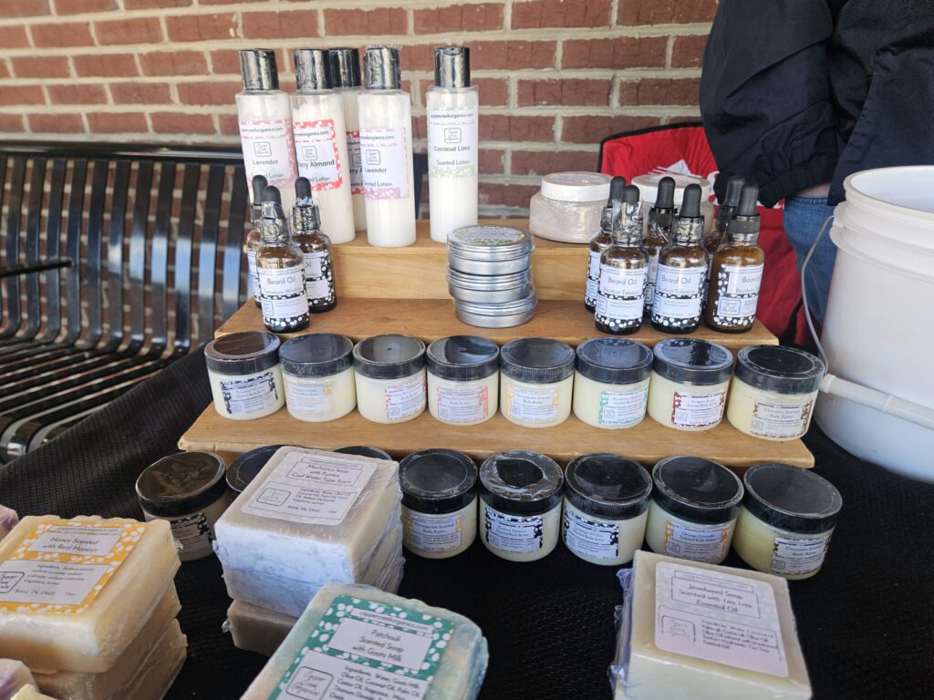 Assorted natural body care products on a wooden display: lotions, beard oils, and soaps from Copper Creek