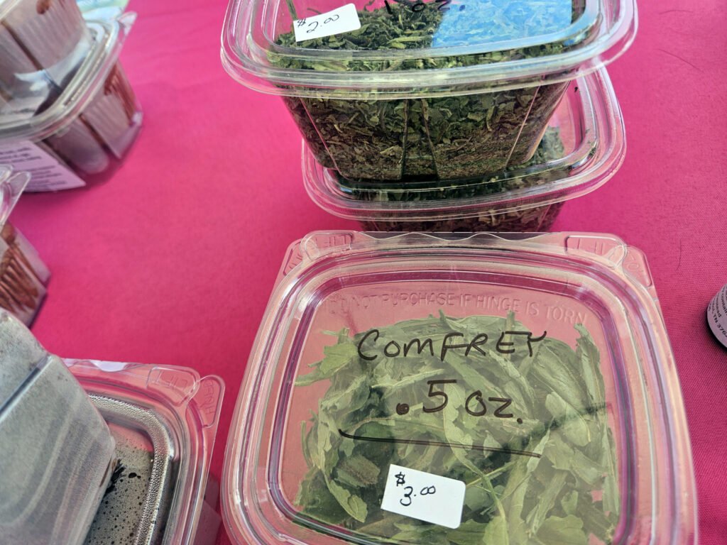 Clear plastic container filled with chopped leafy herbs on a bright pink table, price tag showing .00 for sale