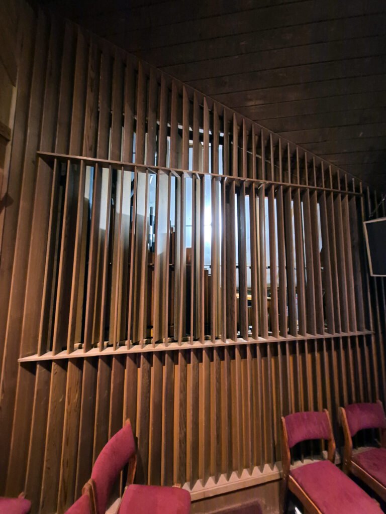 Interior with vertical wooden slats forming a partition the pipes are behind this partition. Photo by Daniel K. Smith