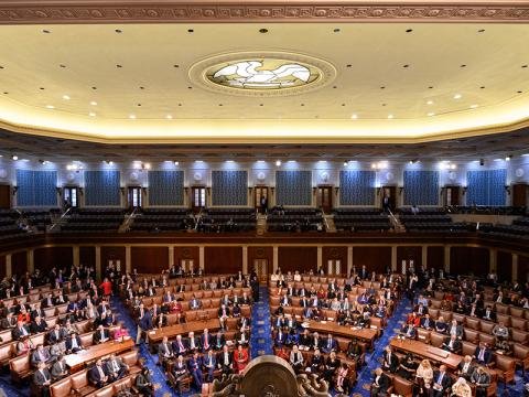 Large legislative chamber filled with delegates seated in rows around a central podium/dais.