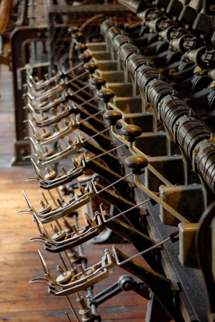 Close-up of a row of black-handled levers and metal controls on an old industrial machine in a workshop.