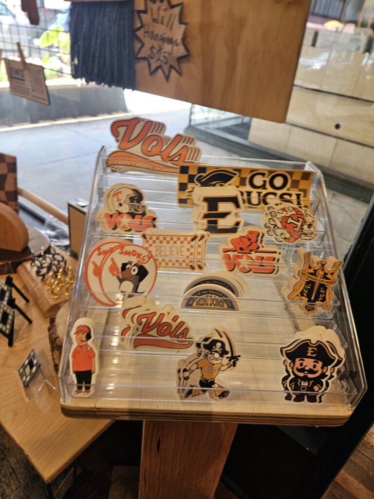 Clear plastic rack filled with orange and white stickers, including a prominent'Vols' logo and vintage cartoon characters.
