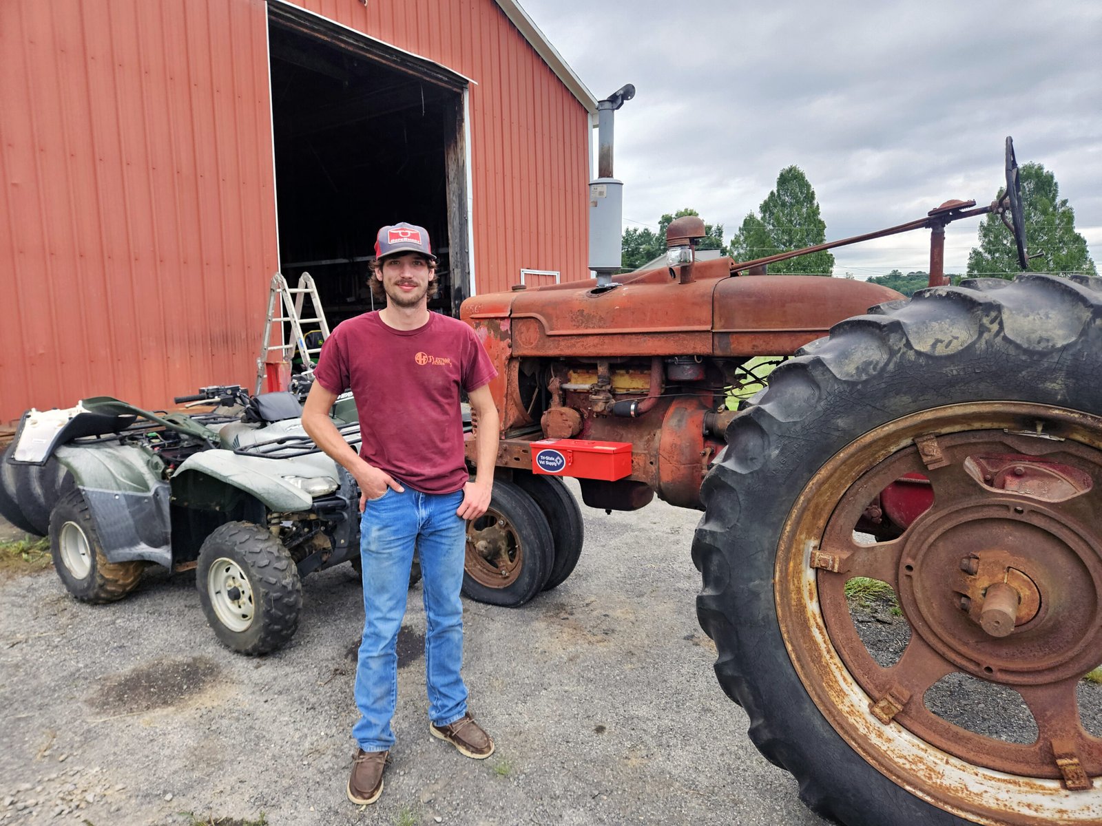 Jackson Fleenor in front of the barn standing next to his early 1940s Farmall M