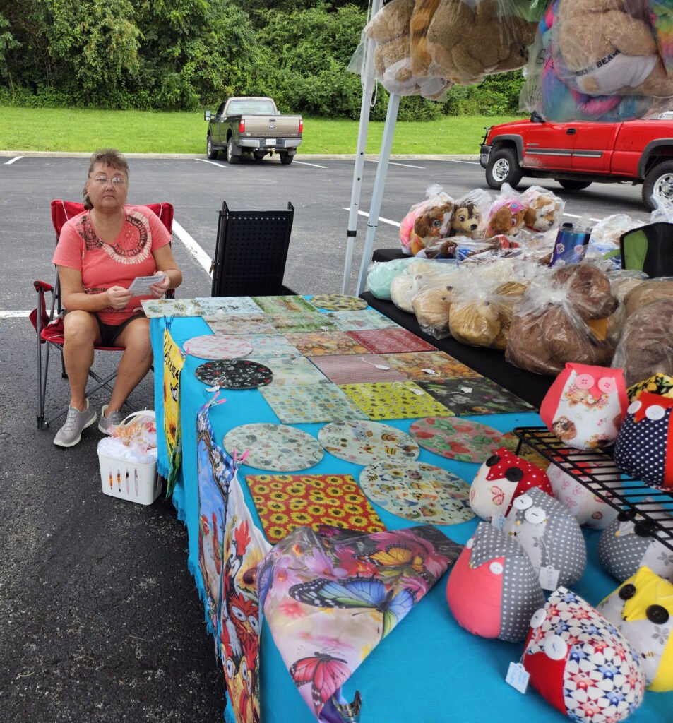 A vendor selling Welcome signs, stuffed items, jewelry, and other items.