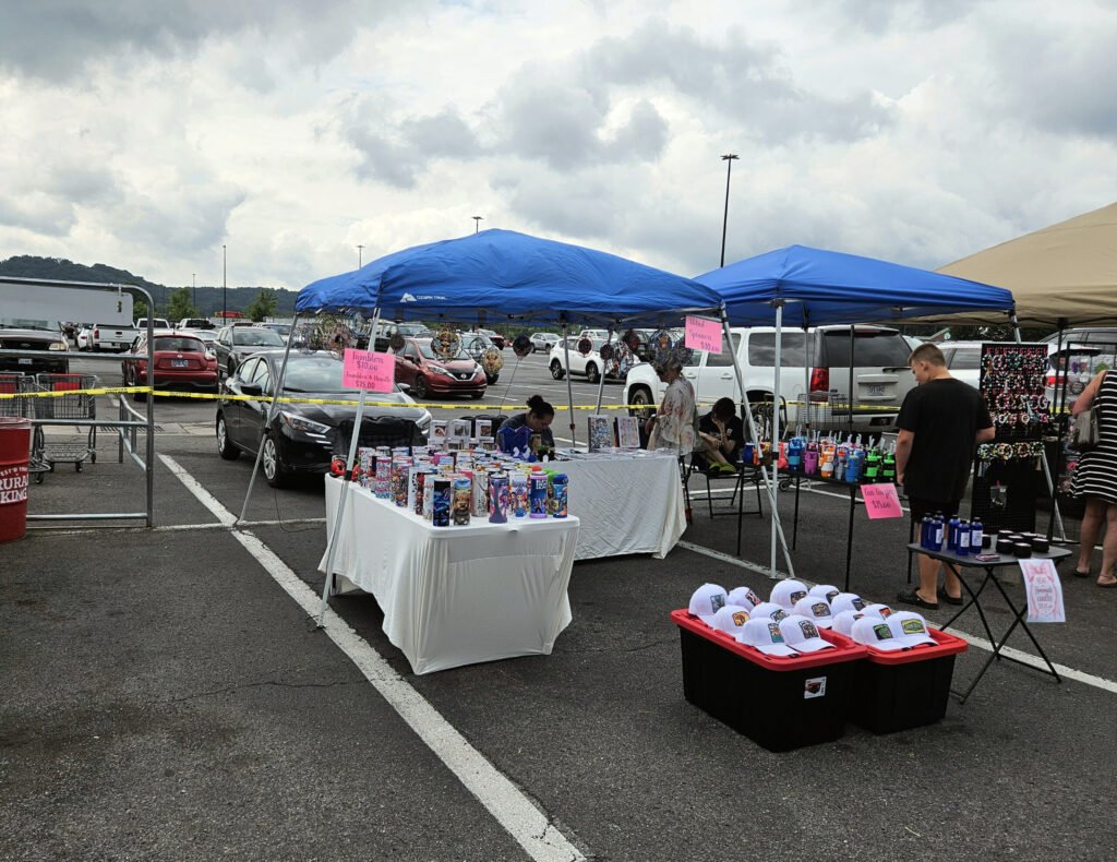 A vendor selling caps with messages on them and tumblers with artwork.