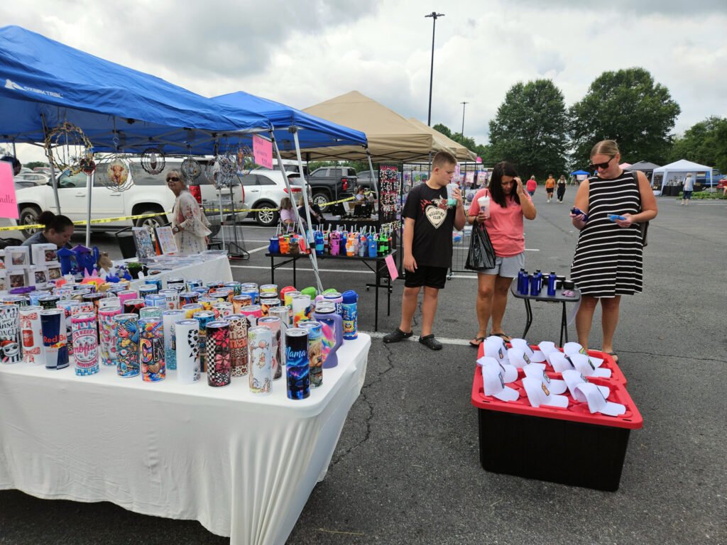 A vendor selling caps with messages on them and tumblers with artwork.