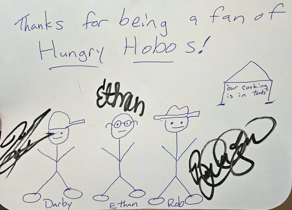 An autographed card with stick figures of Darby, Ethan, and Rob